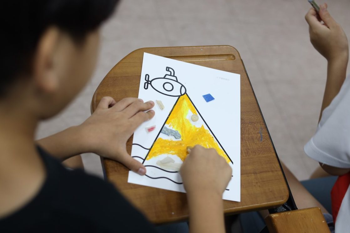 孩子在海廢拼貼教材體驗中塗色，專注創作的畫面