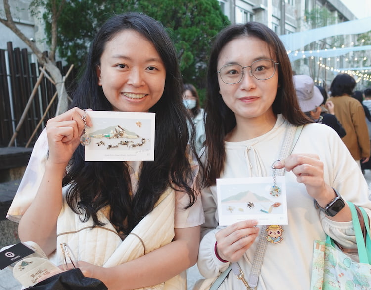 兩位參與者在市集現場完成海廢拼貼明信片，展示各自的創作成果。
